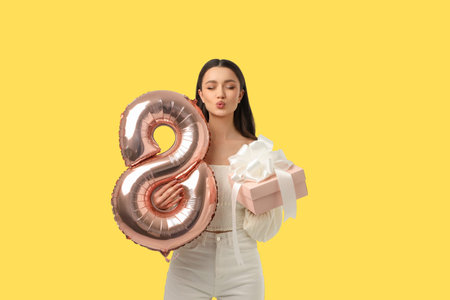 Young woman holds a pink gift and balloon for celebration