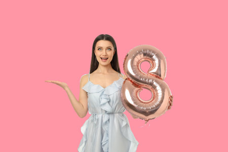 Young woman stands smiling and holds up a number eight balloon