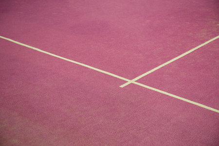 Padel court shows pink surface with white lines for play