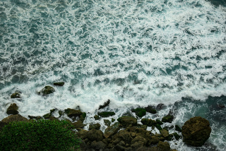 Water flows over rocks as waves hit the shore in Bali