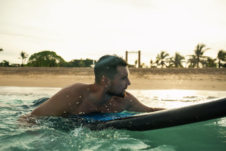 Man paddles a surfboard, enjoying the beach sunset