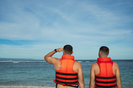 Men are looking out at the ocean while standing on the sandy shore