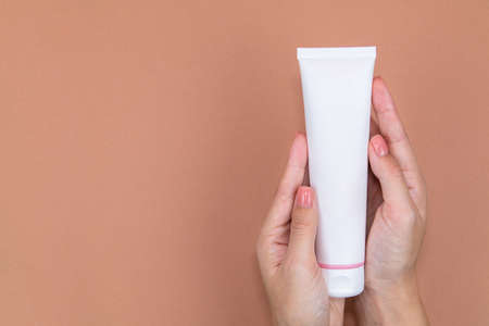 In womens beautiful hands a tube of skin care cream on background with copy space.の写真素材