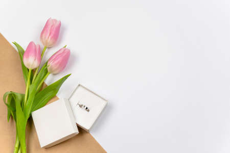 Pink tulips with ring as a gift on white background with crafting paper. Mother's Day, Valentine's...