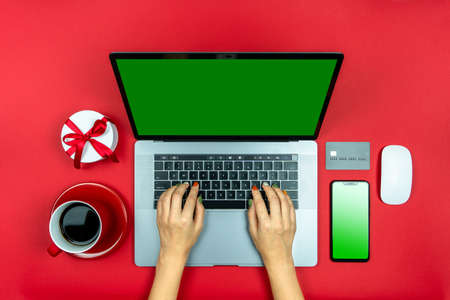 Top view of the hands of a young girl sitting at a laptop on the table. For the holidays, she...