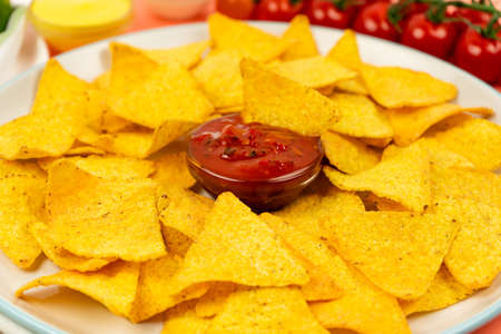 Mouth-watering nachos chips on a white plate and a spicy sauce for a delicious vegetable meal.の写真素材