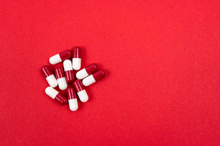 Red and white capsules on a red background. Healthcare concept. Copy space.の写真素材