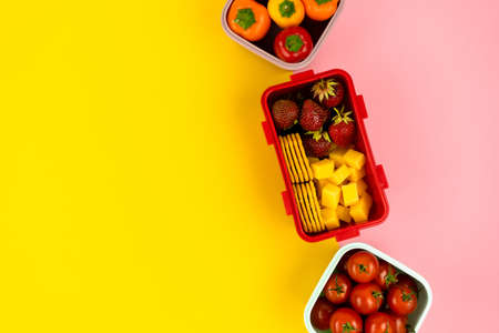 School lunch boxes for storing food and a quick lunch with vegetables and fruits on colored backgrounds. Healthy food and strength.の写真素材