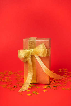 Golden gift box with bow on red background with stars.の写真素材