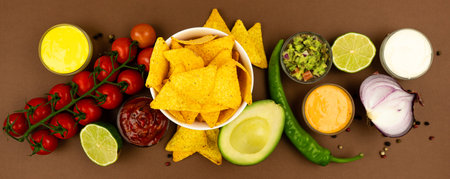 A plate of nachos corn chips with sauces and ingredients, red onion, avacado, peppers and tomatoes.の写真素材