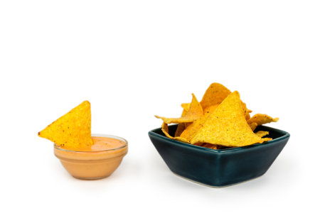 Serving of crispy nachos in a plate with cheese and sauce on a white plate.の写真素材
