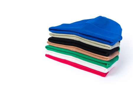 Warming stylish handmade beanie hats in different colors stacked in a stack on a white background...