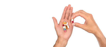 A man's hand is full of a large pile of different pills on white background. Treatment concept. Copy spaceの写真素材