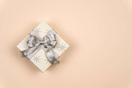 Christmas gift box with a silver ribbon and bow on a delicate background with a place for the inscription of wishes. Chrismas time. Copy spaceの写真素材