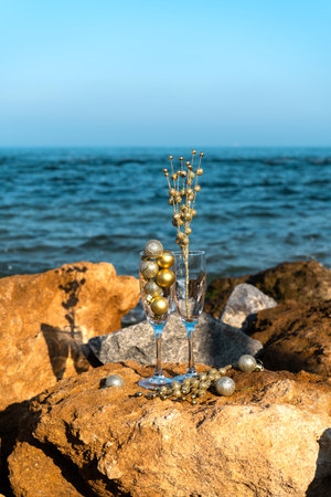 Glasses with New Year's decorations on a rocky beach by the sea, New Year's celebration. Vertical photoの写真素材