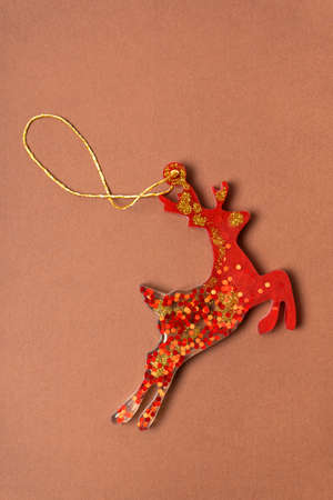 Red Christmas epoxy deer on a brown background. Christmas decorations on the tree. Vertical photographyの写真素材
