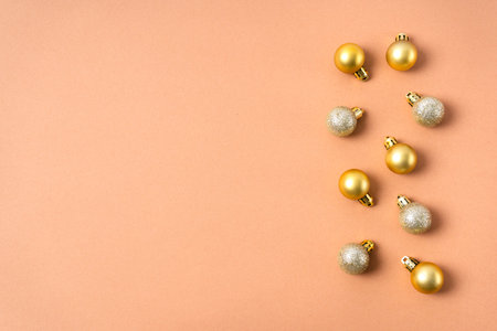 Gold glittering balls on a Christmas tree are laid out in a row on a beige background. Christmas decorations. Copy spaceの写真素材