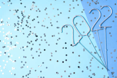 Happy New Year 2022! Flat composition with numbers of upcoming holiday made of sparklers with glitter on blue background with copy spaceの写真素材