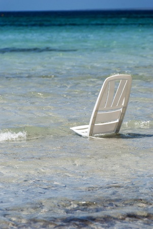 A white beach chair stand in the water at the beach の写真素材