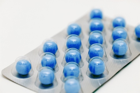 Blue pills in a blister on white background