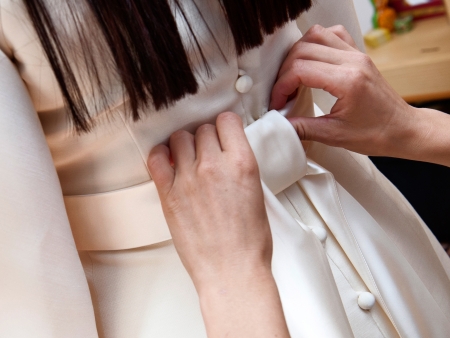 bridesmaid tying bow on wedding dressの写真素材