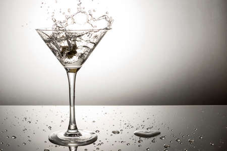 Olive splashing on a martini cocktailの写真素材