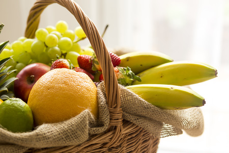 Basket full of fruits on a light background - high keyの写真素材