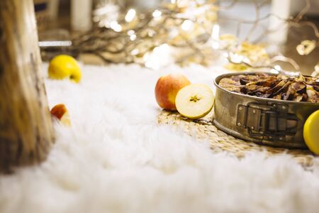 Christmas fruit cake on a table with white fur and apple fruit decorationの写真素材