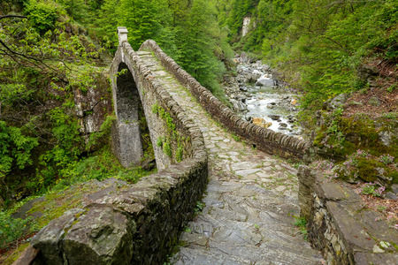 Ponte Romano Intragna Bridge hiding in the valley with beautiful river covered with trees, close to Verzasca village. It is the oldest bridge in Switzerland.の写真素材