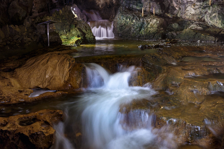St. Beatus Cave and waterfalls above Thunersee, Sundlauenen, Switzerland. Falls are running down the mountain with a green grass and long exposure of waterfallsの写真素材