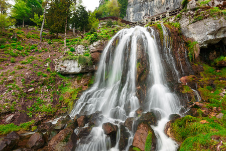 St. Beatus Cave and waterfalls above Thunersee, Sundlauenen, Switzerland. Falls are running down the mountain with a green grass and long exposure of waterfallsの写真素材