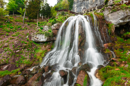 St. Beatus Cave and waterfalls above Thunersee, Sundlauenen, Switzerland. Falls are running down the mountain with a green grass and long exposure of waterfallsの写真素材