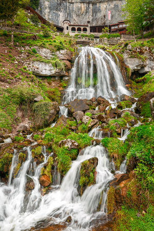 St. Beatus Cave and waterfalls above Thunersee, Sundlauenen, Switzerland. Falls are running down the mountain with a green grass and long exposure of waterfallsの写真素材