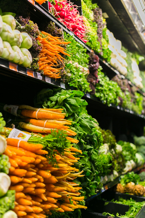 Stacks of fresh vegetable in a grocery  like carrot, salad, onion, and mushrooms in a grocery shopの写真素材