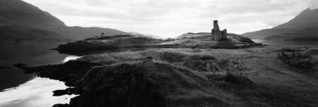 Black and white silhouette of Ardvreck Castle surrounded by water and lit by sunset, located near Lairg, Scotland, UKの写真素材