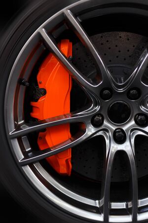 Closeup detail on a big orange sport break, on a sport tire and carbon disk breaks.の写真素材