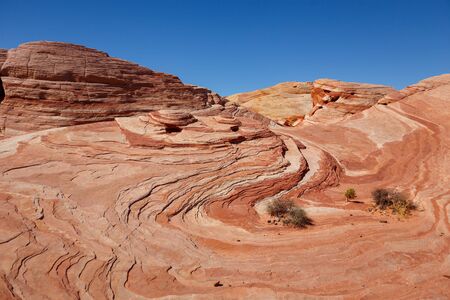 Fire wave with swirly layers of deposited sandstone during wonderful sunny day with blue sky, in Valley of Fire State Park, Nevada, USAの写真素材