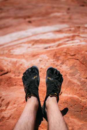 Valley of Fire, Nevada, USA - October 6, 2019: Detail on a person wearing Vibram Five Finger hiking shoes at Fire wave, Valley of Fire national park,のeditorial素材