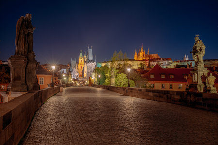Empty Charles Bridge in the center of Prague during first wave of Covid-19 pandemy in the night with blue sky and yellow lightsのeditorial素材