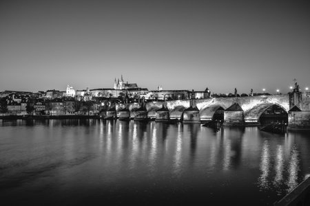 View on Charles Bridge and Prague Castle over Vltava River during early night with wonderful blue sky and yellow city lightsのeditorial素材