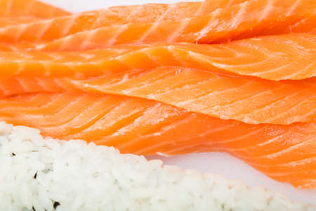 preparing sushi roll, roll and salmon closeup on white boardの写真素材