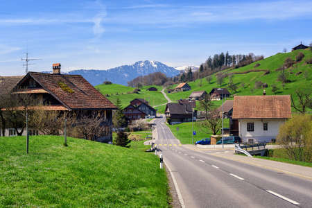 Traditional wooden houses in a little swiss village with snow Alps peak in background, central Switzerlandの写真素材