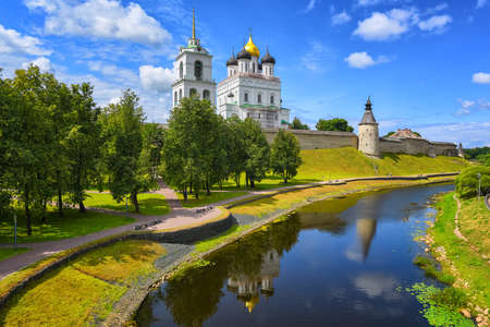 The watch tower, the walls and golden dome of Trinity Church in Pskov Kremlin reflecting in a river, Pskov, Russiaの写真素材