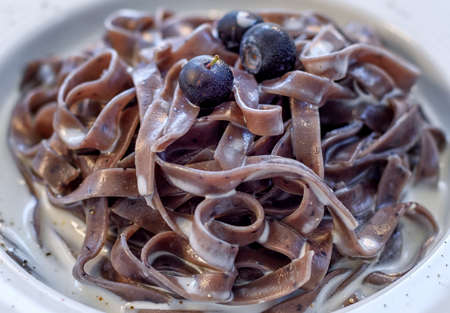 Delicious blueberry tagliatelle pasta with cream sauce, decorated with blueberries, a dish from italian cuisineの写真素材
