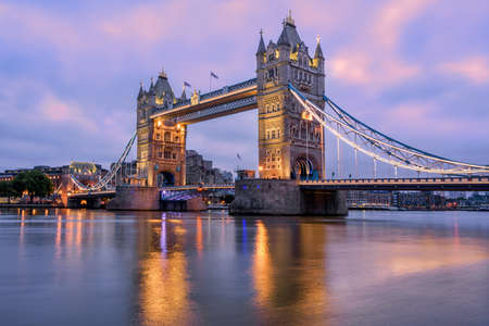 Tower Bridge in London, UK, reflecting in Thames river in dramatic sunrise lightの写真素材