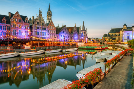 Illuminated historic houses on Graslei quay reflecting in river Leie in the medieval city center of Ghent, Belgiumのeditorial素材