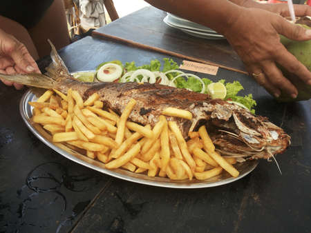 Praia de Cumbuco, CearÃ¡, Brasil - marÃ§o 24 2019 - Desgustar um peixe frito e batata frita,  em frente a praiaのeditorial素材