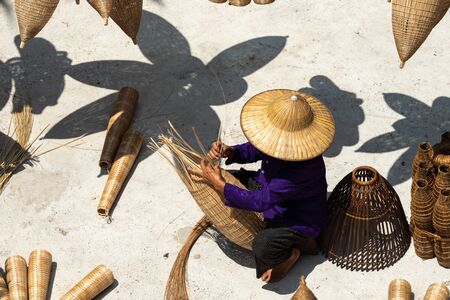 VIETNAM, July 16, 2018 Old Vietnamese craftsman making the traditional bamboo fish trap or weave at the old traditional house in Thu sy trade village, Hung Yen, Vietnam, traditionalのeditorial素材