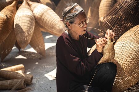 VIETNAM, July 16, 2018 Old Vietnamese craftsman making the traditional bamboo fish trap or weave at the old traditional house in Thu sy trade village, Hung Yen, Vietnam, traditionalのeditorial素材