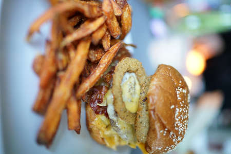 Burger with onion rings eggs and sweet potatoe fries.High quality photoの写真素材